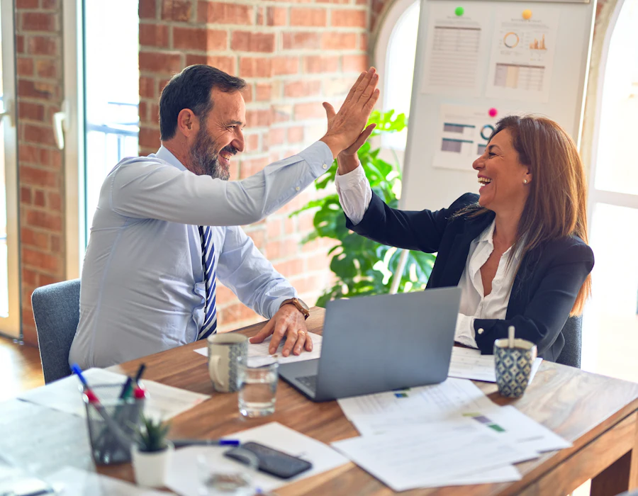 Two colleagues giving a high five across a desk