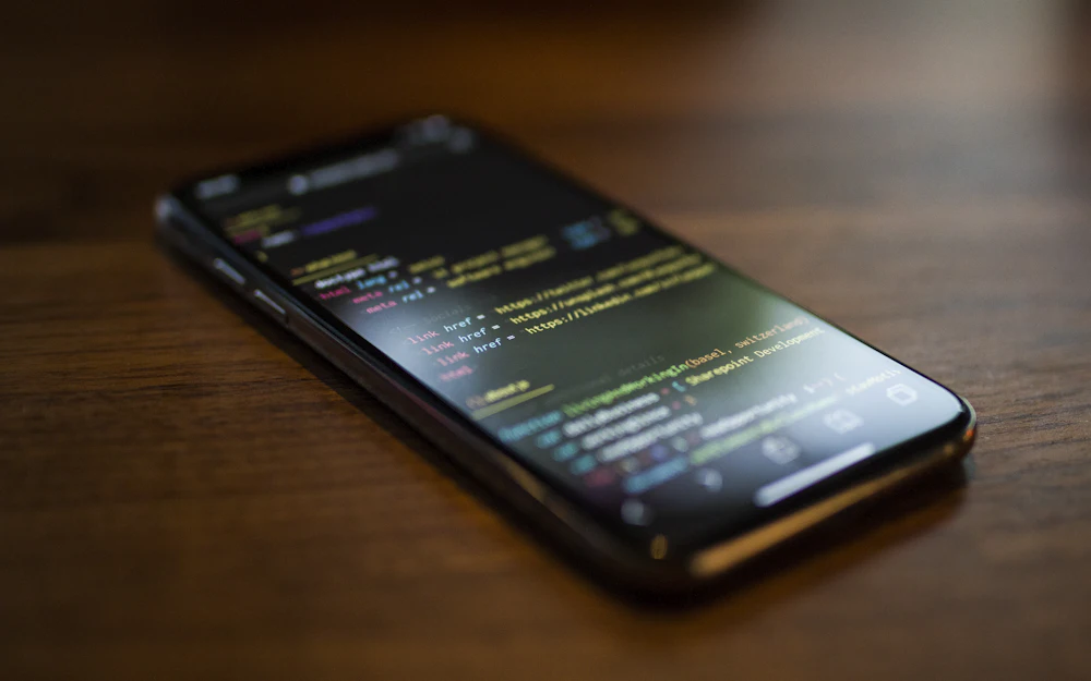 Smartphone lying on a wooden table showing app code