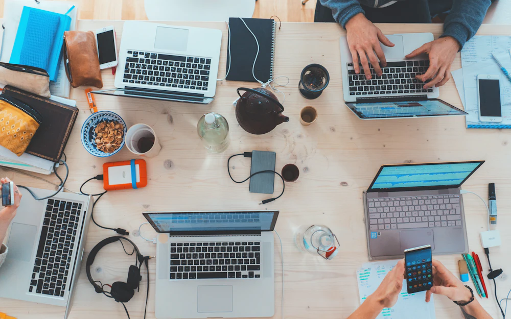 Overhead view of a team working on laptops around a shared desk